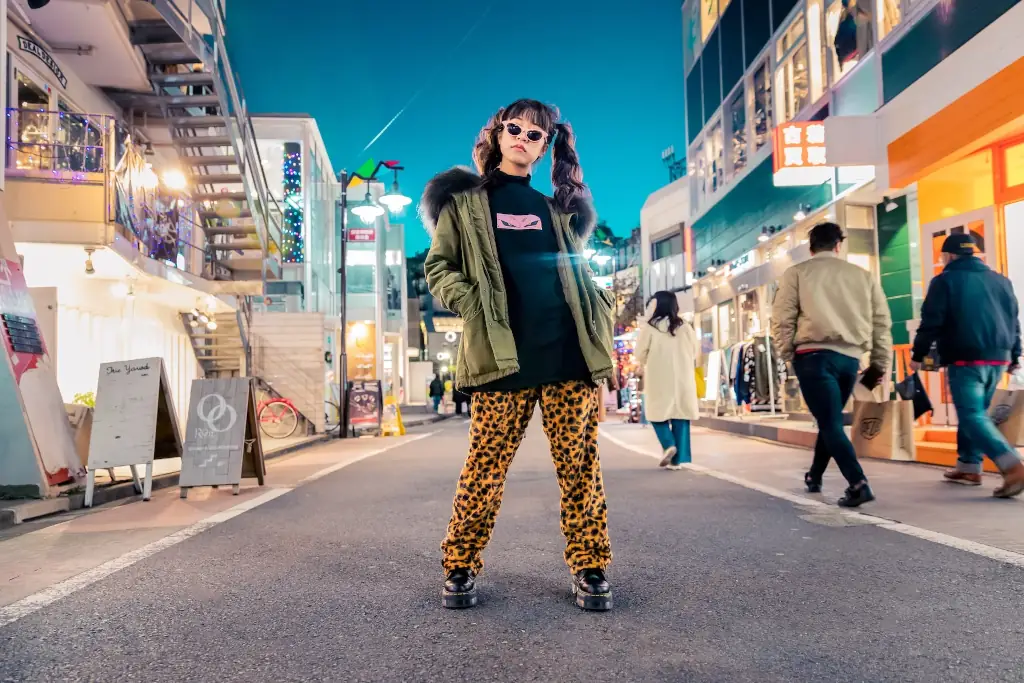 A woman in leopard print pants standing on a street at night.