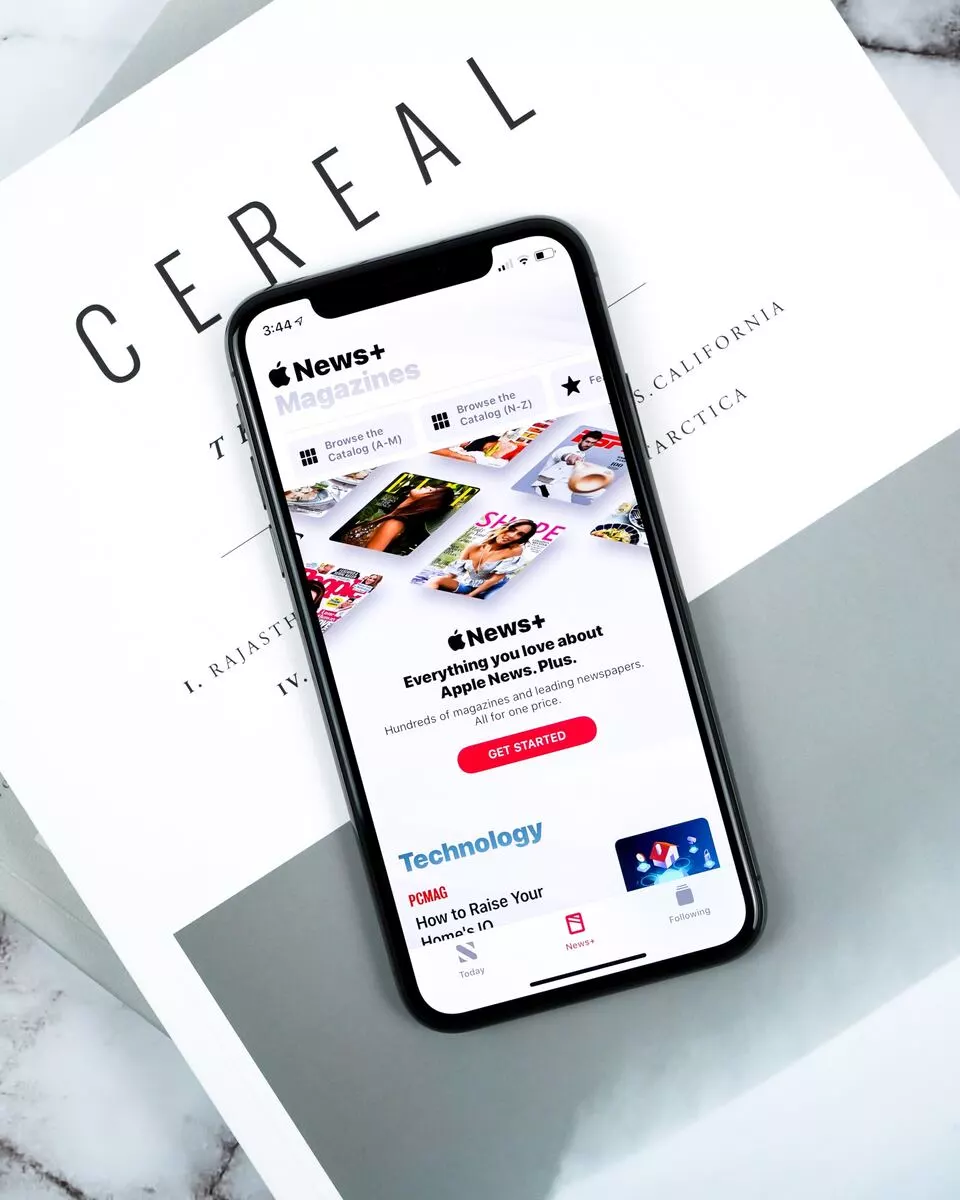 An iPhone is positioned on a table adjacent to a magazine, undergoing a technical SEO audit.