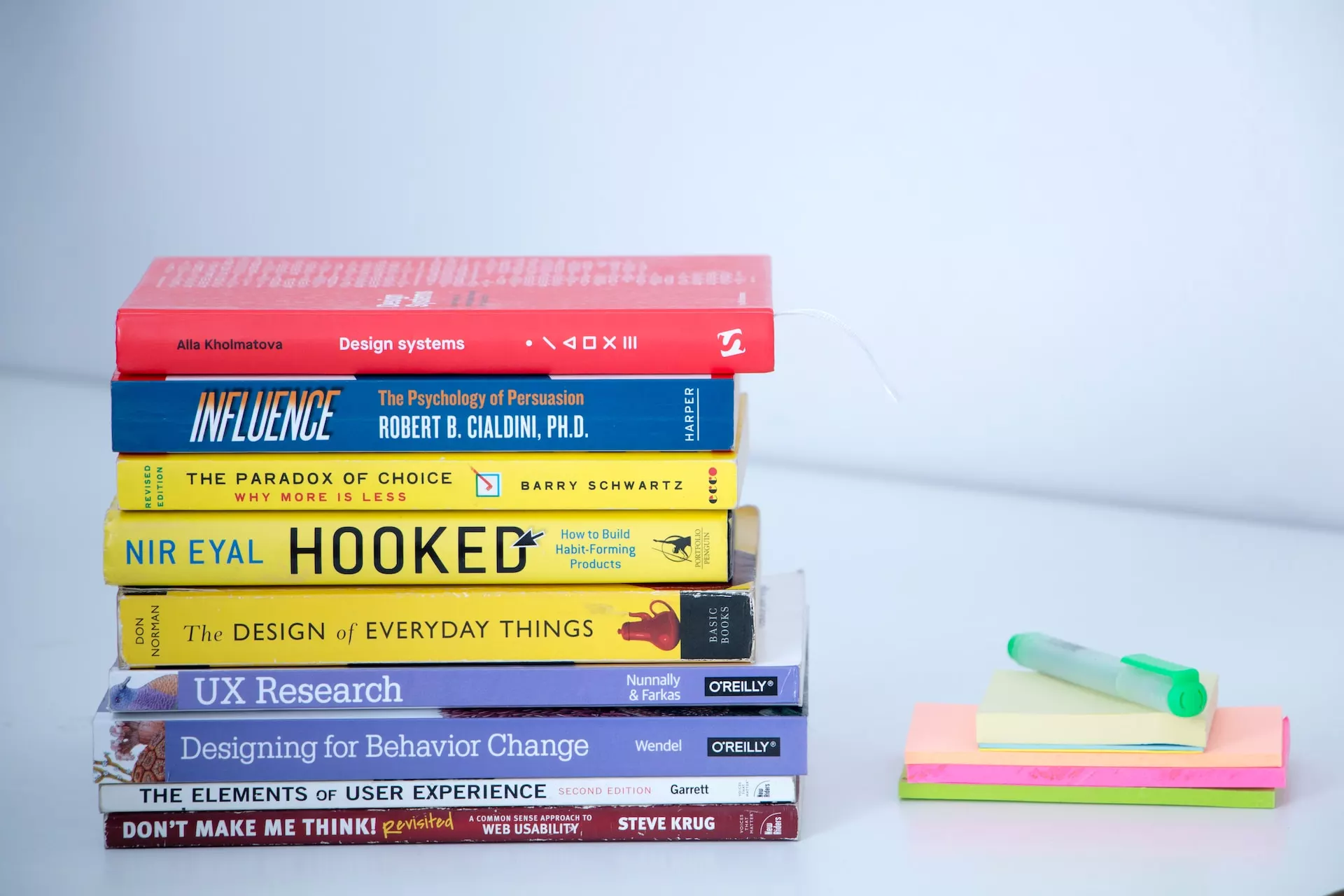 A stack of books on a white table that illustrates the relationship between SEO and design.