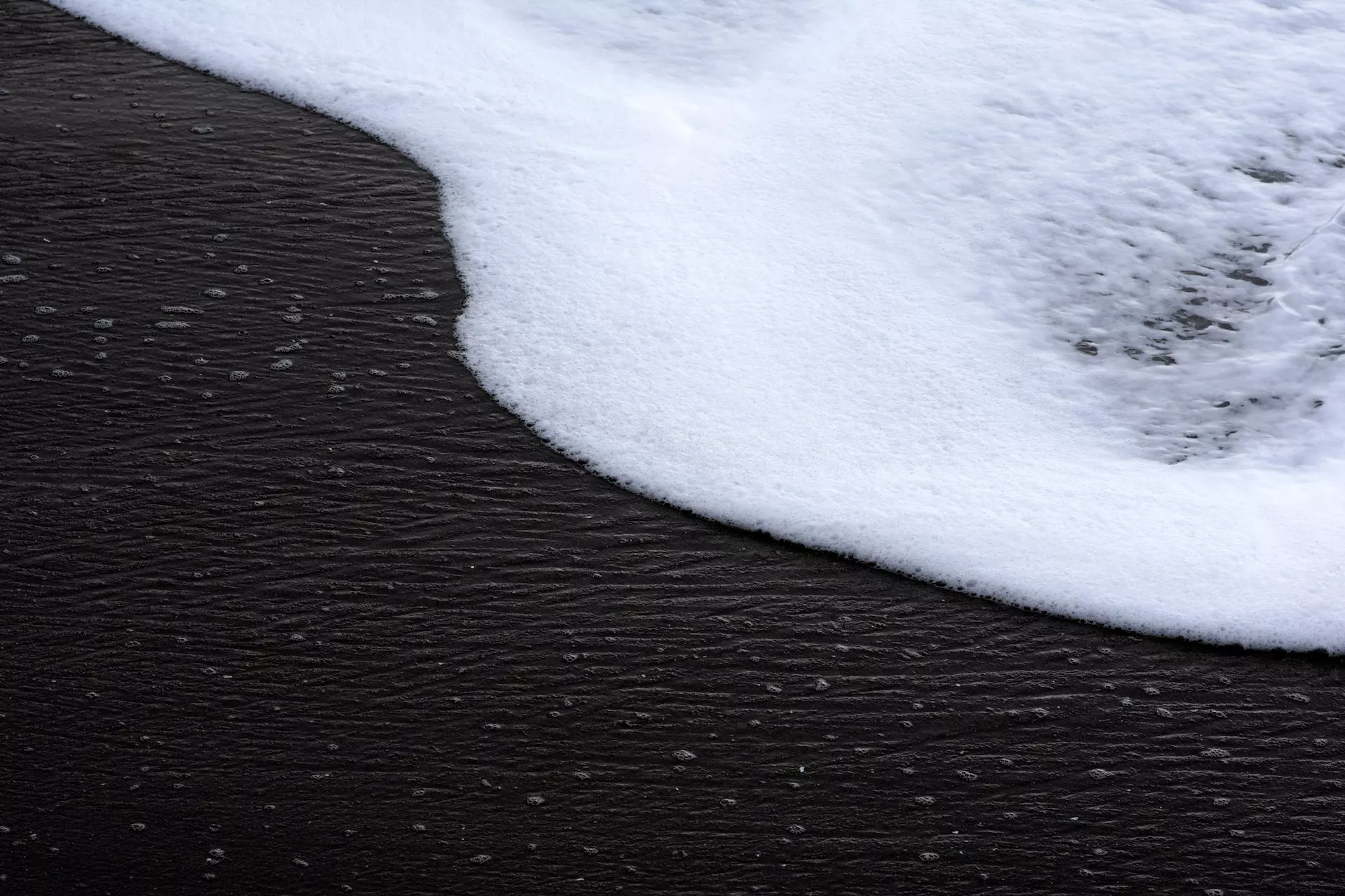 A close up of a wave on a black sand beach illustrating the relationship between SEO and Design.